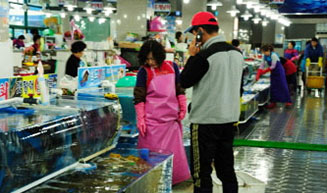 남자가 통화하며 수산시장 안에서 서있는 모습