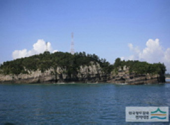 푸른빛 하늘과 구름들이 가파른 돌산뒤로 보이는 추도 전경