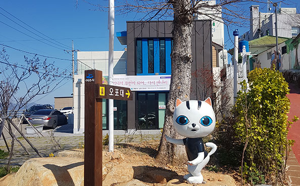 오포대 표지판 뒤로 고양이 조형물이 있다.