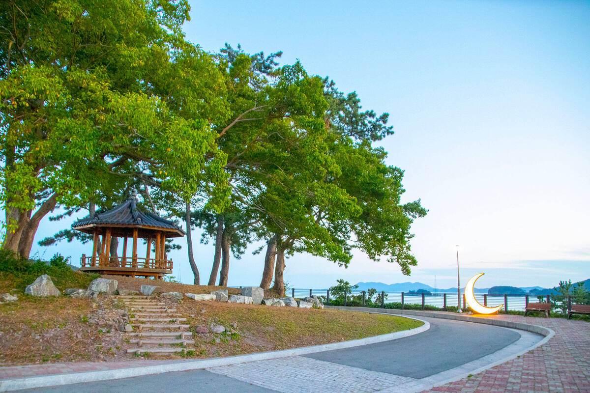 산책로 왼쪽에 쉴수있는 정자가 배치되어 있고 오른쪽에 초승달 조형물과 벤치가 있다