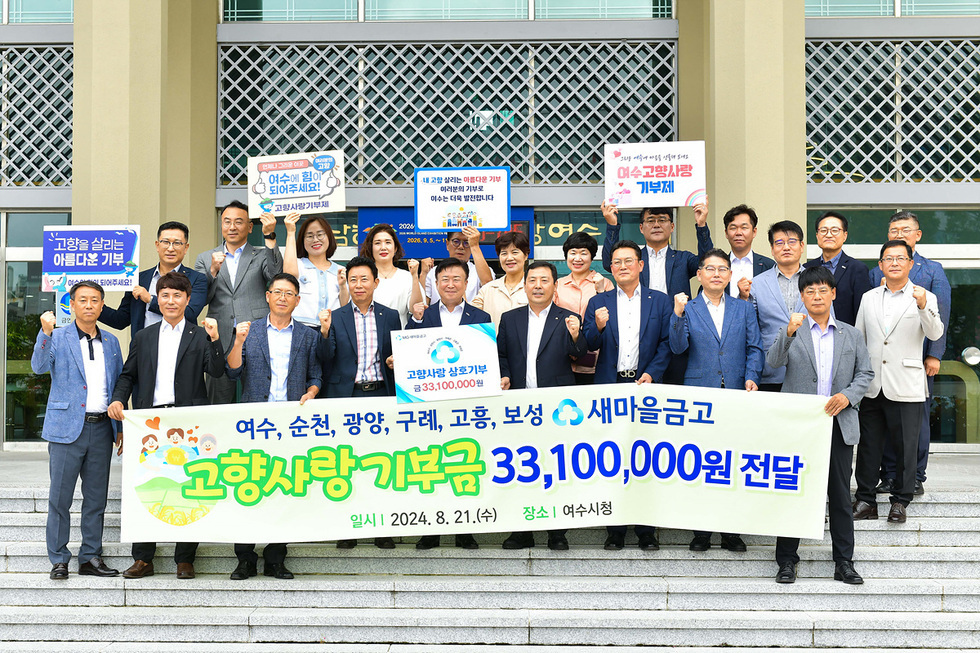 여수시청 앞에서 여러 사람들이 고향사랑 기부금 전달식을 진행하고 있으며, 기부금 액수와 관련된 현수막을 들고 있다.