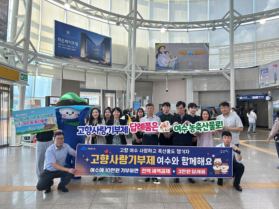 여수에서 고향사랑기부제를 홍보하는 행사에서 참가자들이 기념사진을 찍고 있다. 현수막에는 기부와 관련된 정보가 적혀 있다.