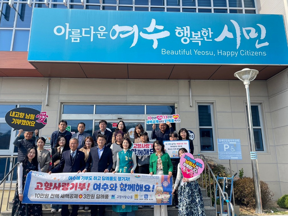 여수시청 앞에서 시민들이 고향사랑기부 캠페인을 홍보하며 단체 사진을 찍고 있다. 배경에는 아름다운 여수 행복한 시민이라는 현수막이 걸려 있다.