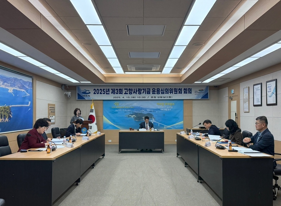 2025년 고향사랑기금 운용심의위원회 회의가 열리고 있는 장면으로, 참석자들이 회의 테이블에 앉아 있으며, 배경에는 관련 현수막이 걸려 있다.