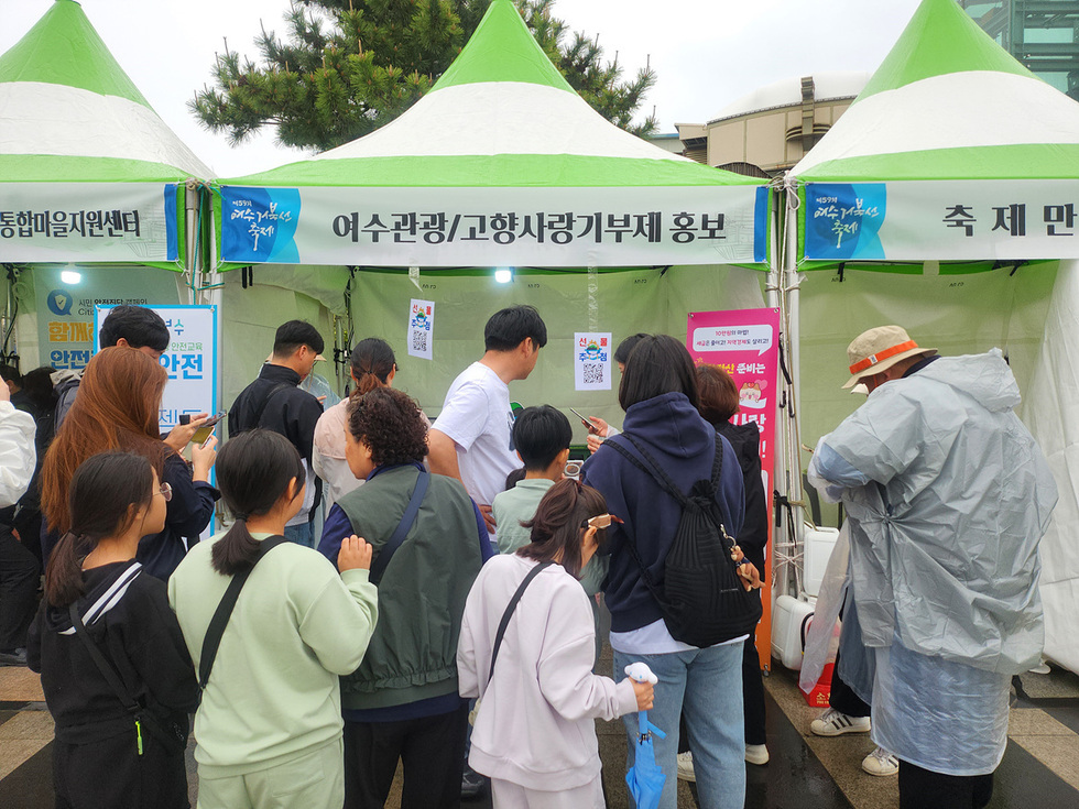 사람들이 여수광광과 고향사랑기부제를 홍보하는 부스 앞에 모여 있는 모습이다.