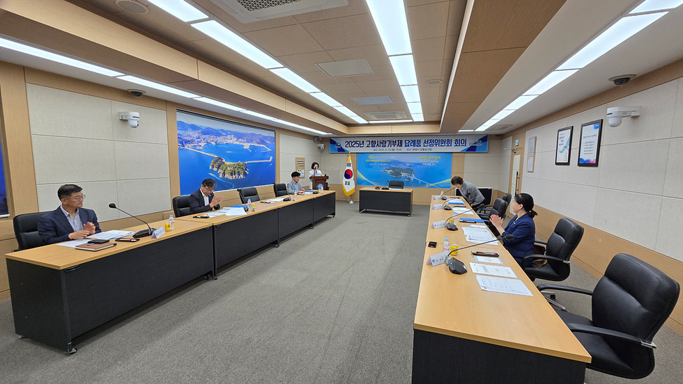 회의실에서 고상사랑가게제 담배품 선정위원회 회의가 진행되고 있으며, 참석자들이 회의에 집중하고 있다.