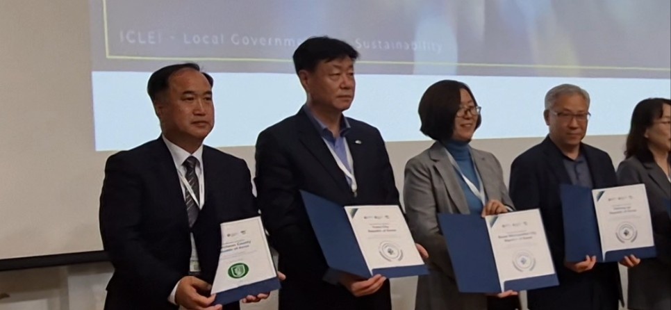 여수시 관계자들이 무대 위에서 국제 기후·에너지 시장협약(GCoM) 이행평가 최고 등급 수상 현수막과 상장을 들고 기념 촬영하는 모습