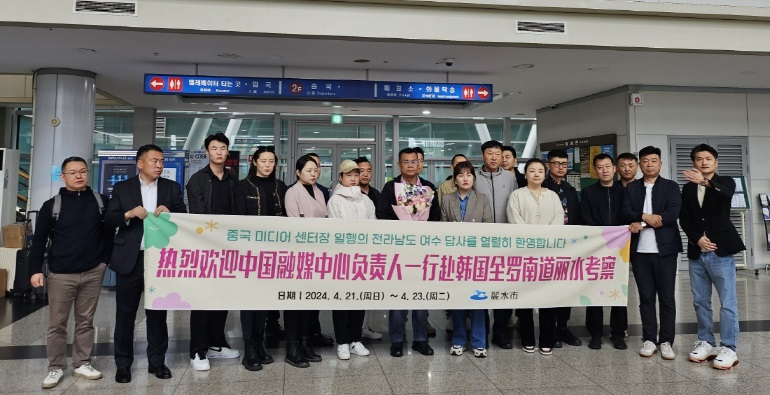 여수에서 중국 미디어 센터 관계자들이 모여 전라남도 탐사를 환영하는 현수막 앞에 서 있다.