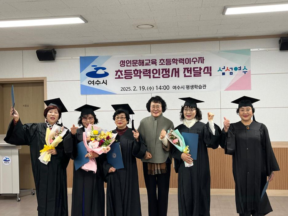여수시에서 성인문해교육 초등학력인정서 전달식이 열리고 있으며, 졸업생들이 학위복을 입고 기념사진을 찍고 있다.