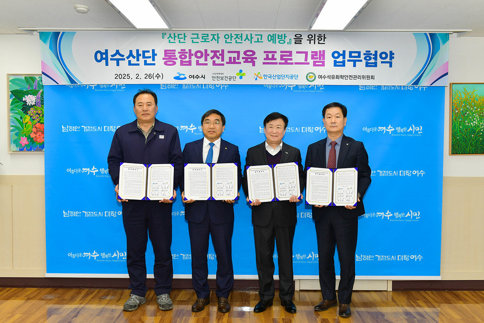 여수시에서 여수산단 통합안전교육 프로그램 업무협약을 체결한 장면으로, 네 명의 남성이 협약서를 들고 서 있다.