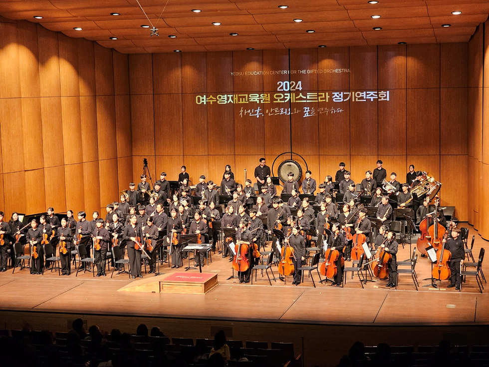 여수영재교육원 오케스트라가 정기연주회를 진행하는 모습으로, 많은 학생들이 무대에서 연주하고 있다.