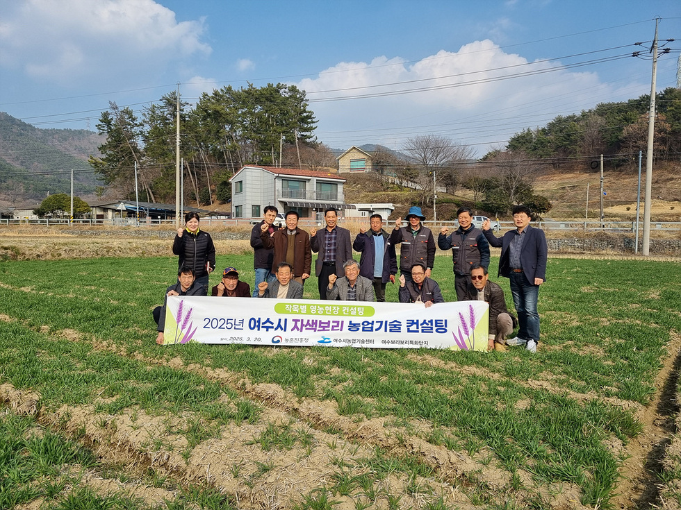 여수시에서 자색보리 농업기술 컨설팅을 위해 모인 농업 관계자들이 현수막 앞에서 포즈를 취하고 있다.