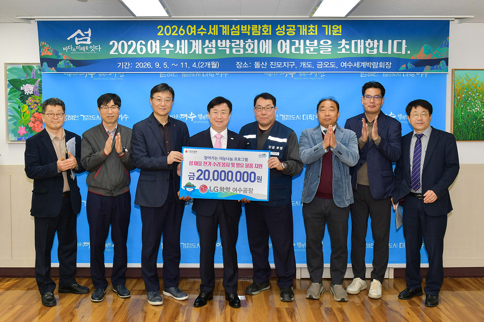 여수세계섬박람회 성공개최를 기원하는 행사에서 여러 명의 남성이 기념사진을 찍고 있으며, 가운데 남성이 큰 금액의 지원을 발표하고 있다.