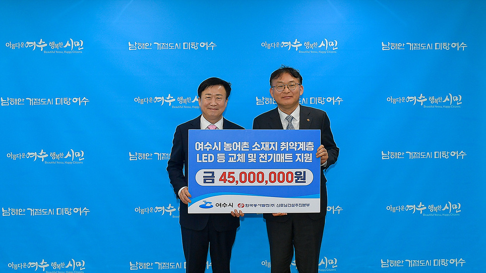 여수시에서 두 사람이 LED 교체 및 전기매트 지원에 관한 내용을 담은 현수막을 들고 기념사진을 찍고 있다.