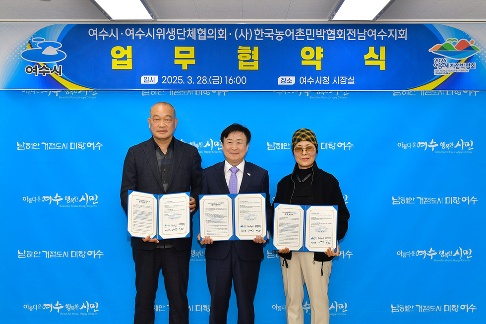 여수시청 시장실에서 여수시와 여수시위생단체협의회, 한국농어촌민박협회전남여수지회 간의 업무협약식이 진행되고 있다. 참석자들이 협약서를 들고 있다.