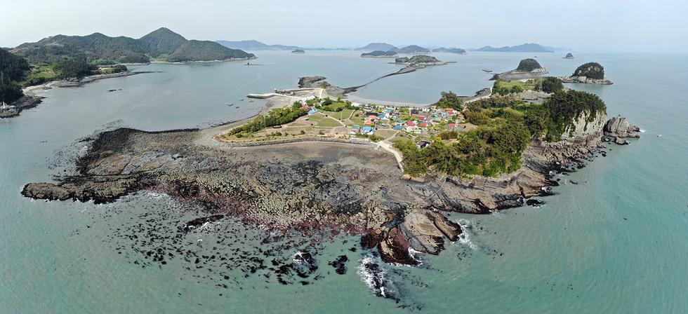바다에 둘러싸인 작은 섬의 전경으로, 섬 중앙에는 여러 채의 집들이 보이고 주변에는 바위와 해안선이 형성되어 있다.