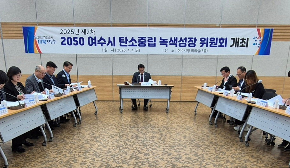여수시청 회의실에서 2050 여수시 탄소중립 녹색성장 위원회 회의가 진행되고 있다. 참석자들이 회의 자료를 검토하고 있다.