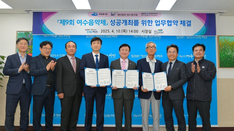 여수시에서 제9회 여수음악제 성공개최를 위한 업무협약을 체결하는 장면으로, 여러 관계자들이 협약서를 들고 서 있다.
