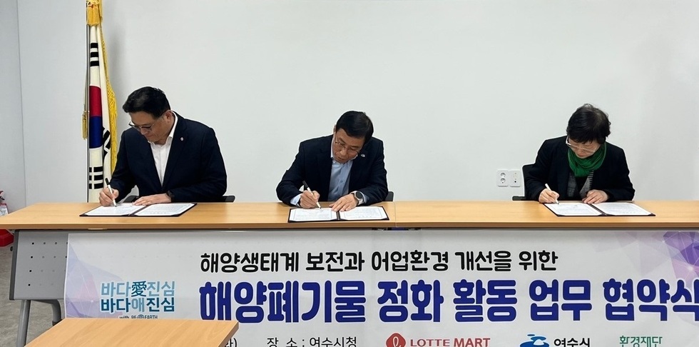 여수시에서 해양생태계 보전과 어업환경 개선을 위한 해양폐기물 정화 활동 업무 협약식이 진행되고 있다. 세 명의 관계자가 서명하고 있다.