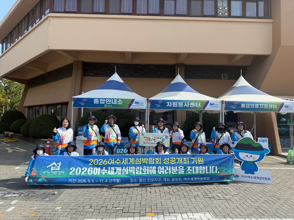 2026여수세계섬박람회 성공개최를 기원하는 자원봉사자들이 종합안내소 앞에서 포즈를 취하고 있다.