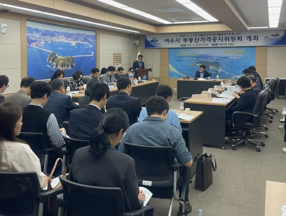 여수시청에서 부동산가격공시위원회가 개최되고 있으며, 참석자들이 회의에 집중하고 있다.