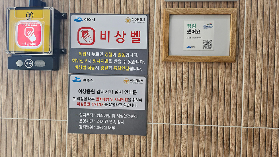 여수시 화장실 내부에 비상벨과 이상음원 감지기기 설치 안내문이 부착되어 있으며, 비상벨 사용 시 경찰이 출동하고 허위신고는 처벌된다는 내용이 포함되어 있다.