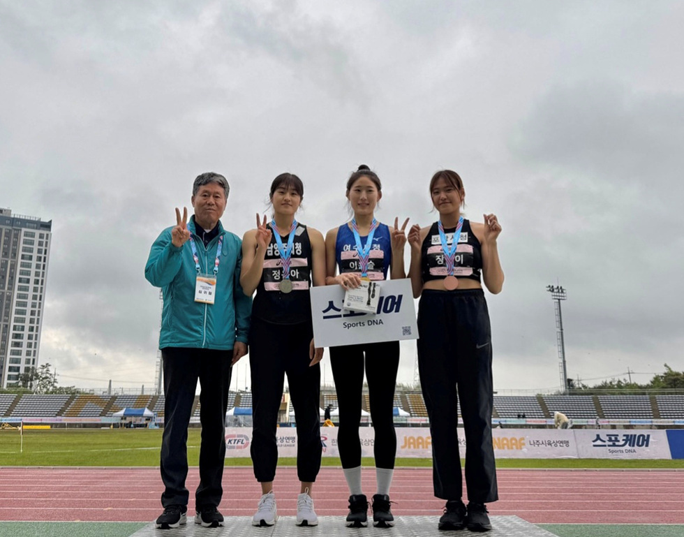 운동선수들이 메달을 목에 걸고 기념사진을 찍고 있다. 한 남성과 세 명의 여성 선수들이 함께 포즈를 취하고 있다.