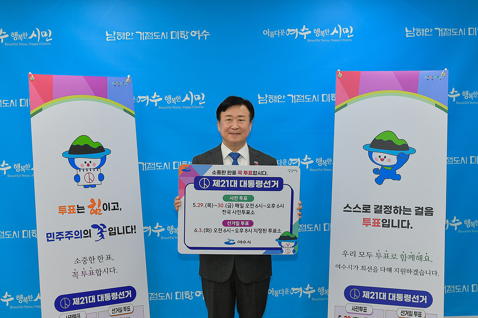 여수시에서 제21대 대통령선거를 홍보하는 장면으로, 한 남성이 투표 관련 안내판을 들고 있다. 배경에는 여수시의 슬로건과 투표 일정이 적힌 현수막이 있다.