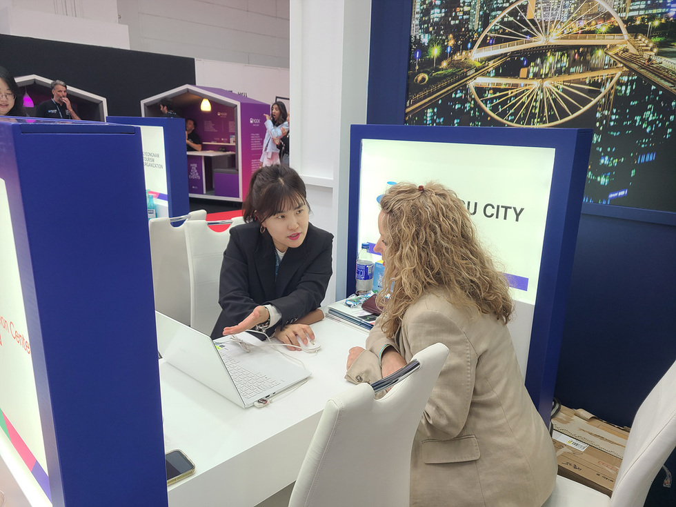 부산시 부스에서 한 여성이 다른 여성과 대화하며 정보를 제공하고 있다.