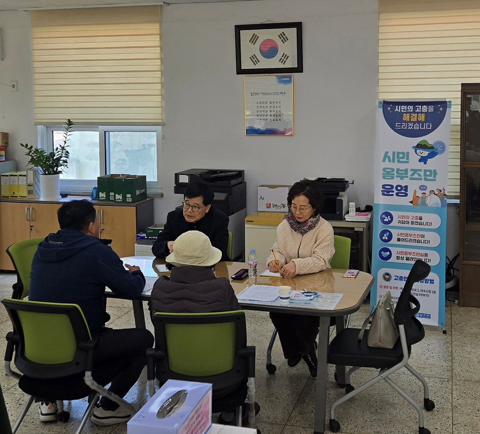 시민 옹부조단 운영을 위한 상담 장면으로, 테이블에 앉은 세 명의 상담자와 두 명의 시민이 대화하고 있다. 배경에는 관련 안내 배너가 보인다.