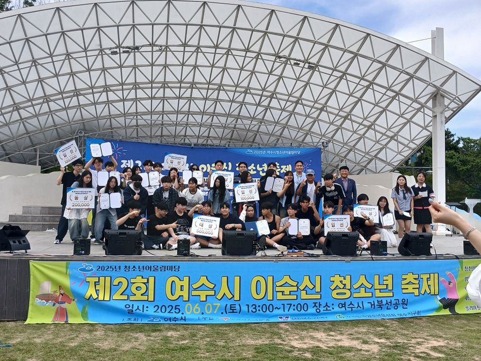 여수시에서 열린 제2회 이순신 청소년 축제에서 참가자들이 기념사진을 찍고 있다. 배경에는 축제 정보가 적힌 현수막이 걸려 있다.