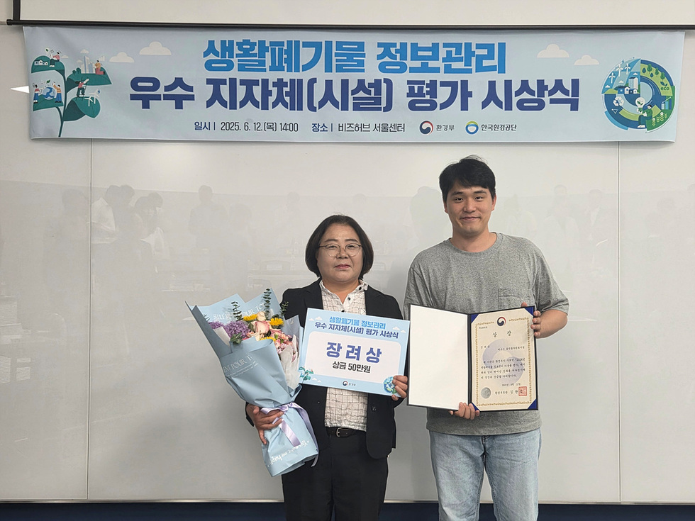 2025년 6월 12일 비즈허브 서울센터에서 생활폐기물 정보관리 우수 지자체 평가 시상식이 열리고 있으며, 한 여성과 남성이 상장과 꽃다발을 들고 기념사진을 찍고 있다.