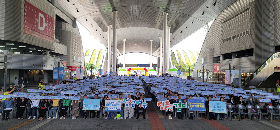 여수시니어클럽 회원들이 삼성연수 청춘을 걷다 행사를 위해 모여 현수막을 들고 있는 모습이다.