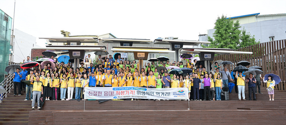 여수시 관계자와 시민들이 단체로 모여 친절 응대와 정직한 가격 실천을 다짐하는 캠페인 현수막을 들고 기념 촬영하는 모습