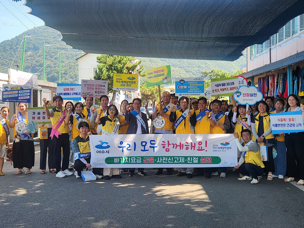여수시와 전라남도 관계자들이 만성리해수욕장 인근에서 바가지요금 근절과 친절 실천을 알리는 캠페인을 진행하며 단체 기념 촬영을 하는 모습