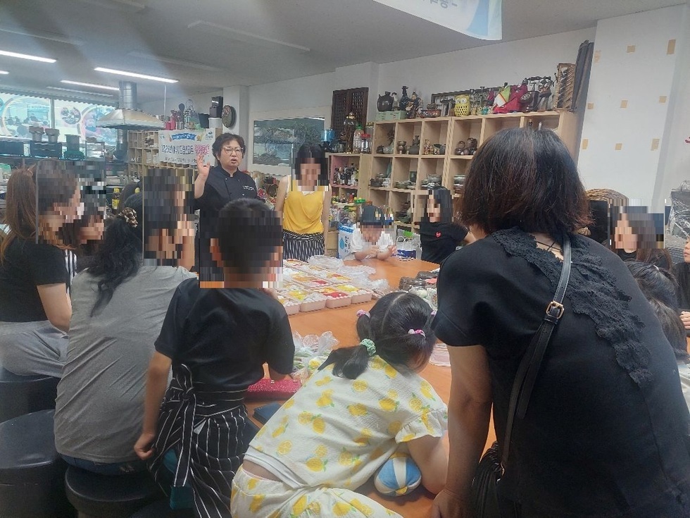 아동과 가족 50명을 대상으로 여수향토문화학원에서 영양교육 및 전통 간식 만들기 체험 프로그램을 운영과 관련하여 가운데 선생님이 설명을 하고있는 사진이다.