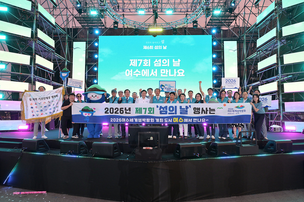 여수에서 제7회 섬의 날 행사를 기념하는 단체 사진으로, 행사 관계자들이 기념 현수막을 들고 있다.