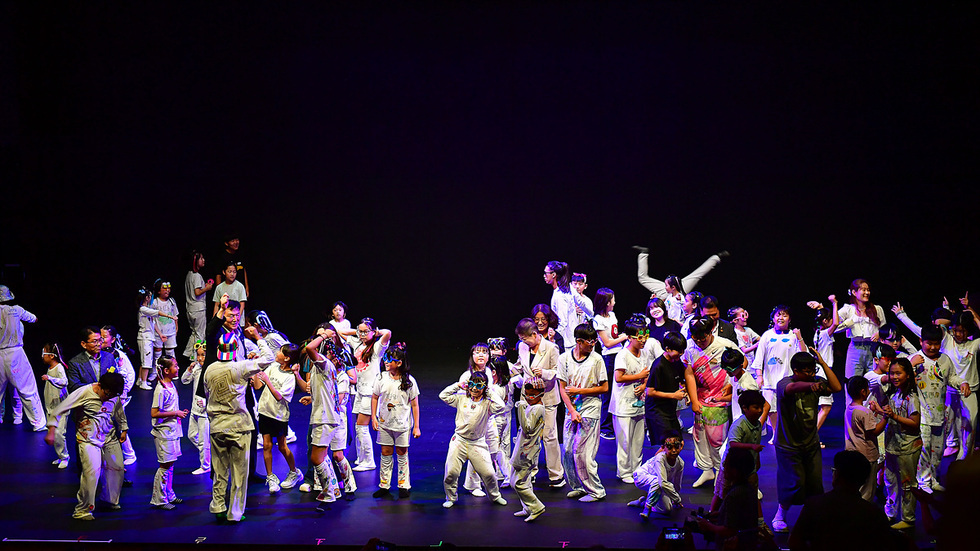 무대 위에서 여러 명의 어린이들이 함께 춤추고 있는 장면이다. 일부는 흰색 의상을 입고 있으며, 즐거운 분위기 속에서 활동하고 있다.