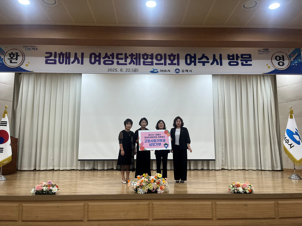 김해시 여성단체협의회가 여수시를 방문하여 기념사진을 촬영하고 있다. 배경에는 여수시의 깃발과 현수막이 보인다.