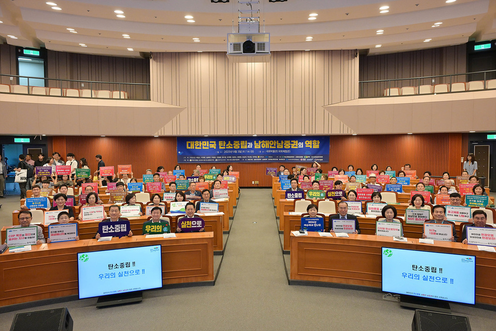 국회의원회관에서 탄소중립과 남해안농업의 역할에 대한 행사에 참석한 사람들. 참석자들이 다양한 메시지가 적힌 현수막을 들고 있다.