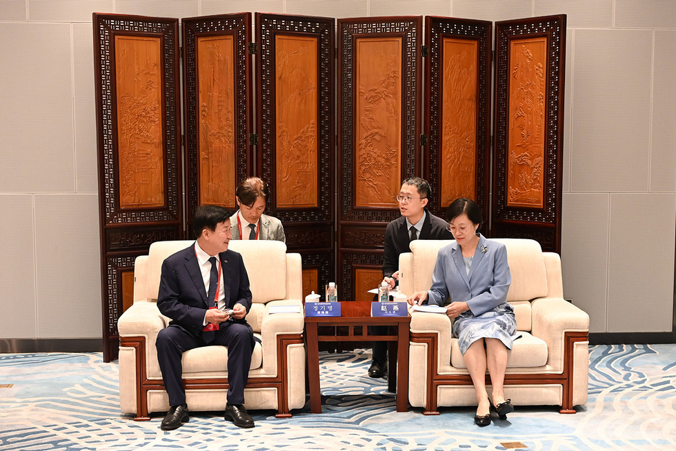 정기명과 류창수 주칭다오 대한민국 총영사이 회의 중 대화를 나누고 있으며, 두 사람 사이에는 통역사들이 앉아 있다.