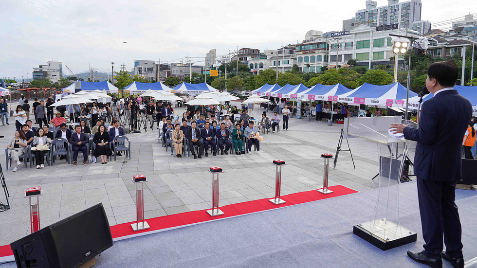 무대 위에서 정기명 여수시장과 사회적경제 유공자 수상자 4명이 함께 서서 표창장을 들고 기념촬영을 하는 모습, 수상자들은 꽃다발을 들고 사회적경제 한마당의 성과를 보여줌.
