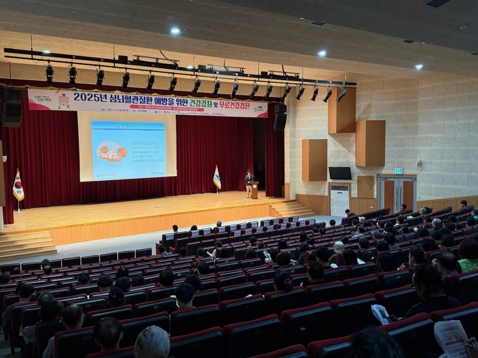 여수문화홀에서 심뇌혈관질환 예방을 주제로 한 건강강좌가 진행되고 있으며, 2025년 심뇌현관질환 예방을 위한 건강강좌 및 무료검진 현수막과함께 강사가 강의 중이다. 참석자들이 강의를 듣고 있다.