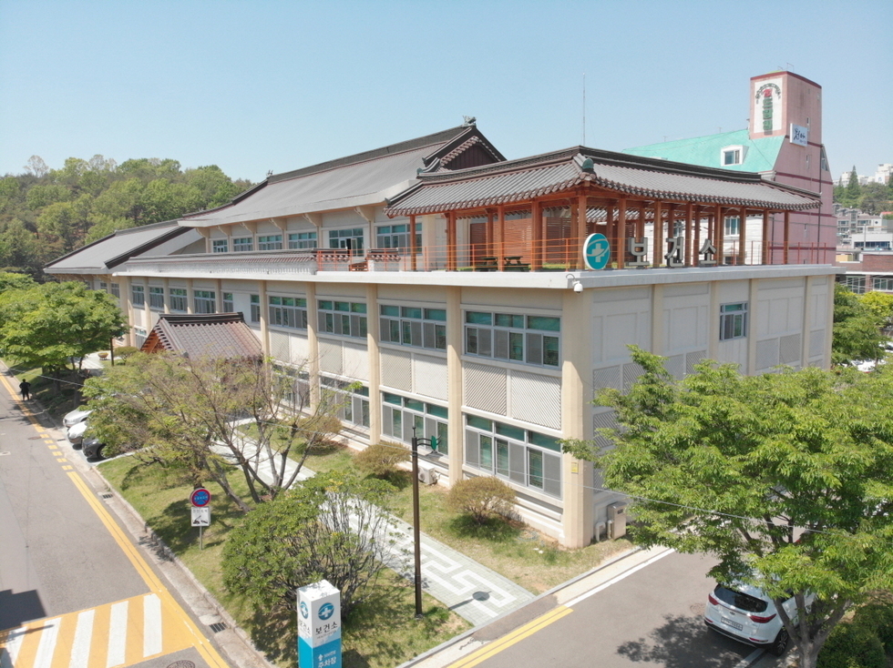 여수시 보건소건물 외관이 보이며, 주변에 나무와 도로가 있다.