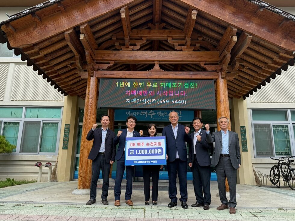 여수시 보건소 앞에서 OB맥주 순천지점이 음식문화 개선을 위한 후원금 100만 원을 전달하는 장면으로, 관계자들이 함께 포즈를 취하고 있다.