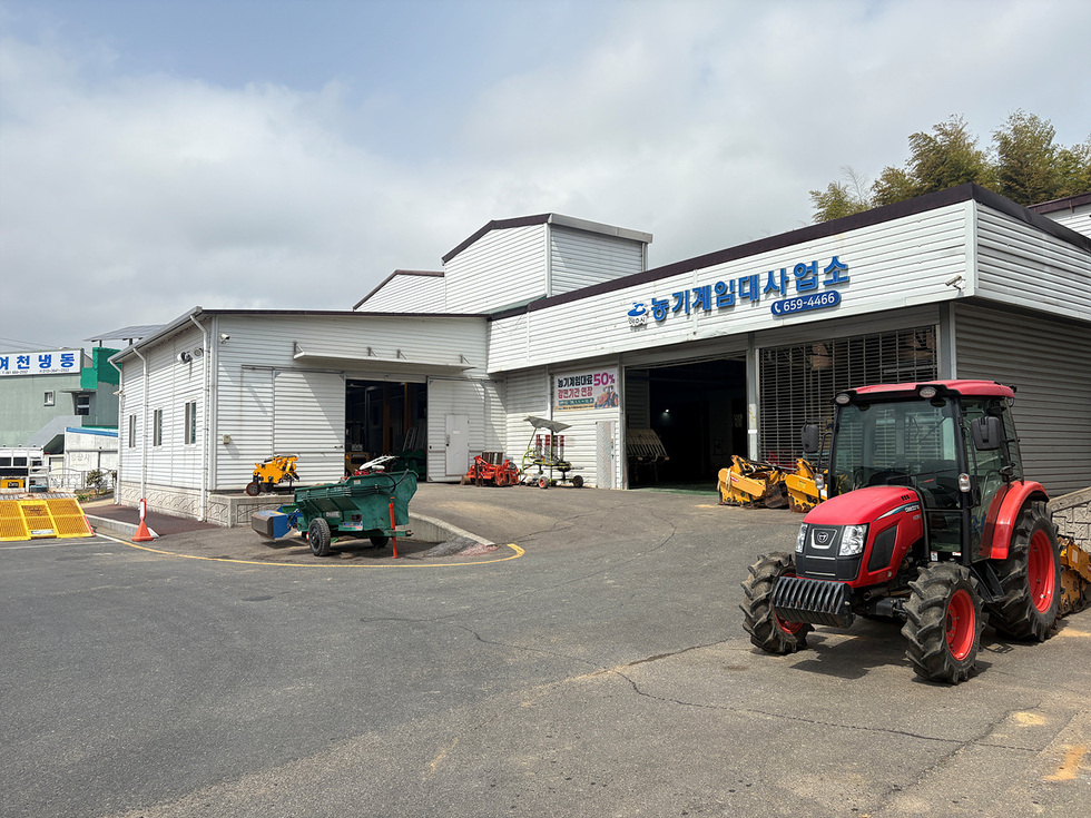 여수시 농기계임대사업소 외관과 농기계들이 보이는 장면으로 농업인들이 농기계를 임대할 수 있는 장소이다.