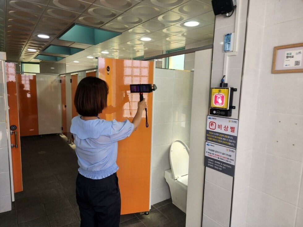 여수시 공중화장실에서 점검을 실시하는 여성의 모습으로, 비상벨이 설치된 화장실 내부가 보인다.