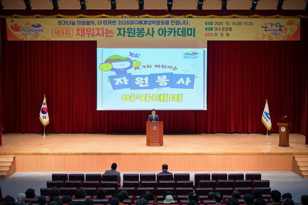 여수문화홀에서 자원봉사자 아카데미가 열리고 있으며, 정기명 여수시장이 무대에서 연설을하고 있다.