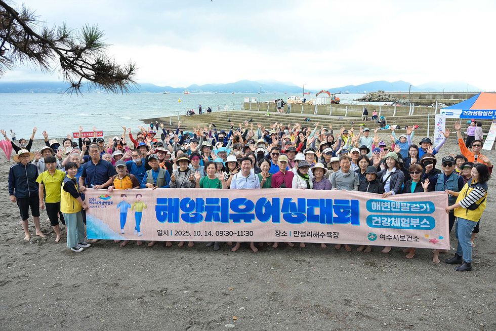 여수 만성리해수욕장에서 열린 해양치유 어싱대회에 200여 명의 참가자들이 모여 기념사진을 찍고 있다. 참가자들은 맨발로 해양치유어싱대회 현수막을 들고 기념사진을 찍고 있다.