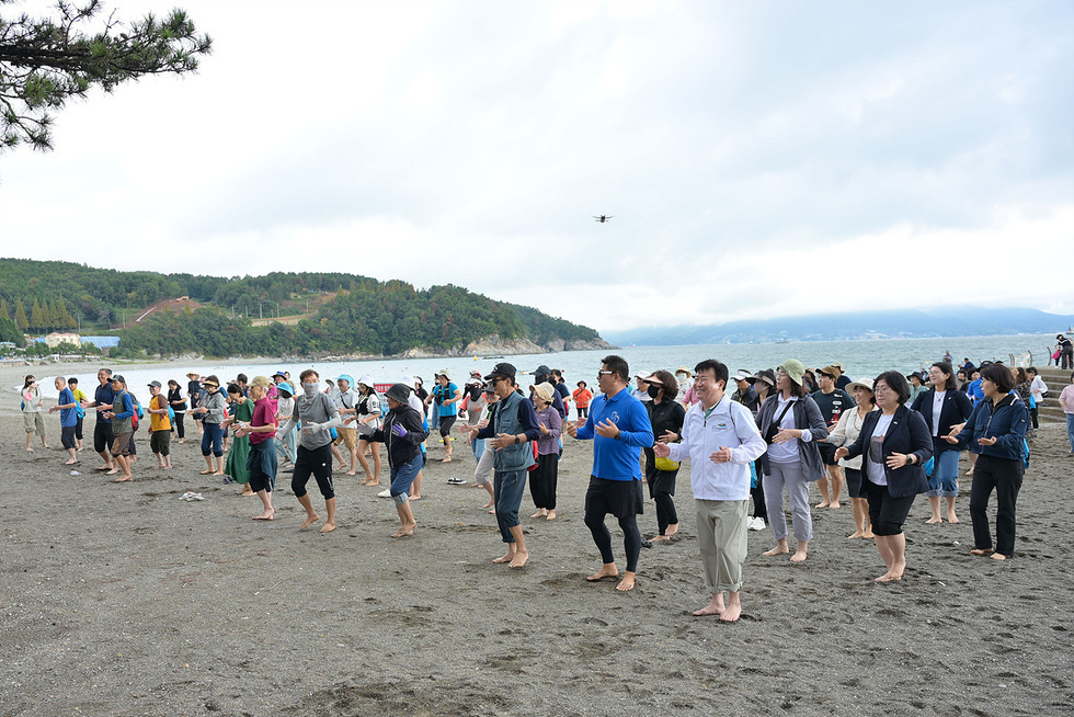 여수 만성리해수욕장에서 200여 명이 참여한 해양치유 어싱대회에서 참가자들이 맨발로 모래 위에서 스트레칭을 하고 있다.